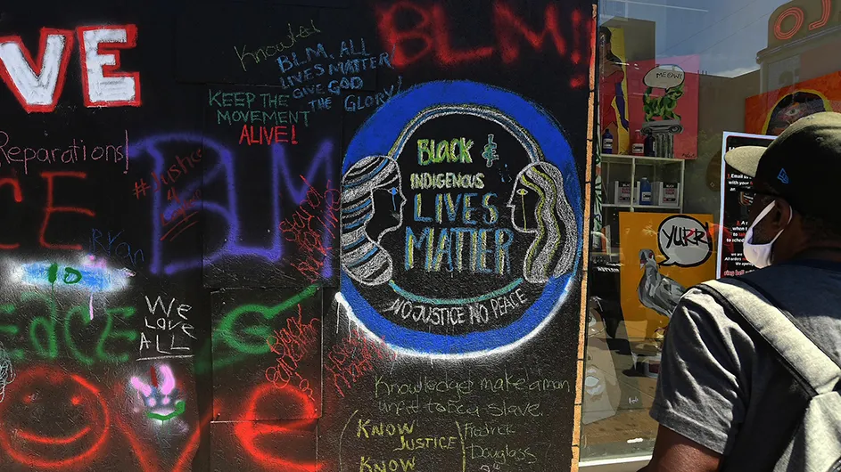 A man looks at street art reading "Black and indigenous LIVES MATTER"