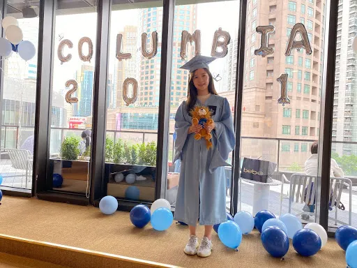 A Columbia grad poses against windows overlooking Shanghai.