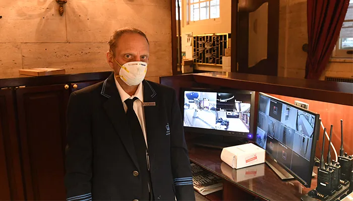 A Columbia Housing doorman stands iwth a mask on. 