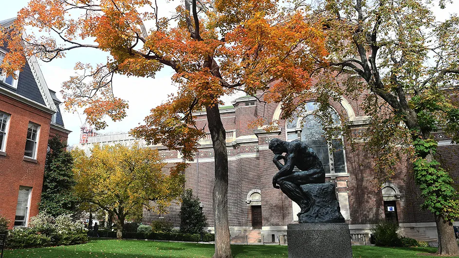 Vibrant orange leaves overhang above the statue of "The Thinker" on Columbia's campus.