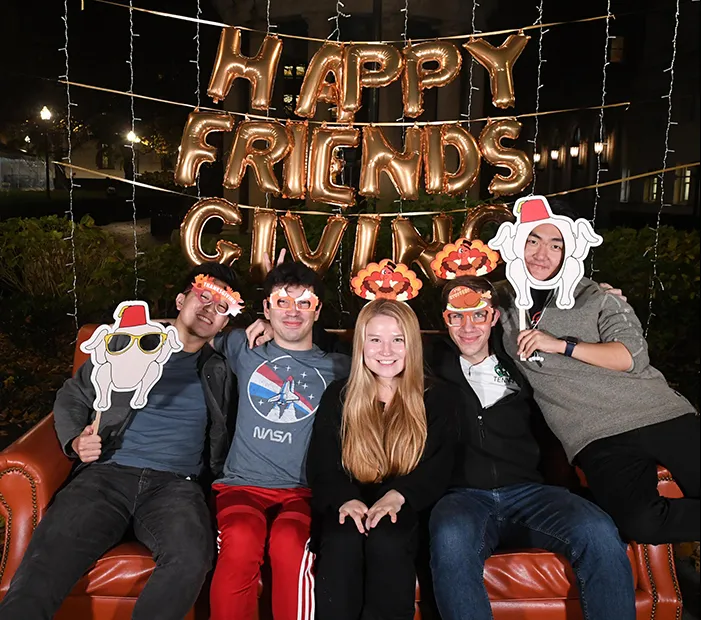 Friends gather together on an orange couch. 