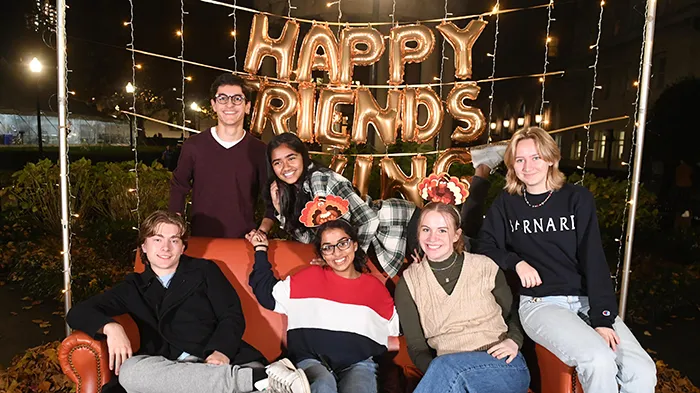 Friends gather together on an orange couch. 