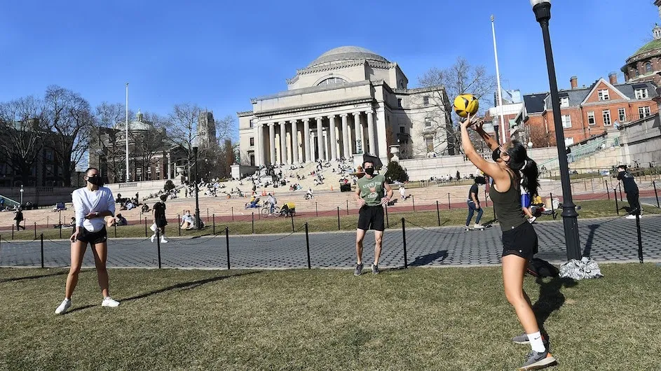 Two Columbia students play volleyball in front of Low Library