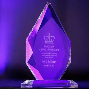 A glass, tear-shaped trophy: the Peter J. Awn Lifetime Service Award inscribed with Columbia President Lee C. Bollinger's name.