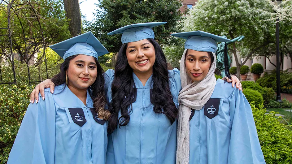 Three Barnard grads in cap and gown. 