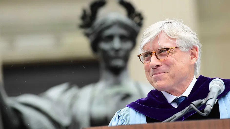 Lee Bollinger, a man with light hair, in a graduate robe standing at a lectern during the graduation ceremony. 
