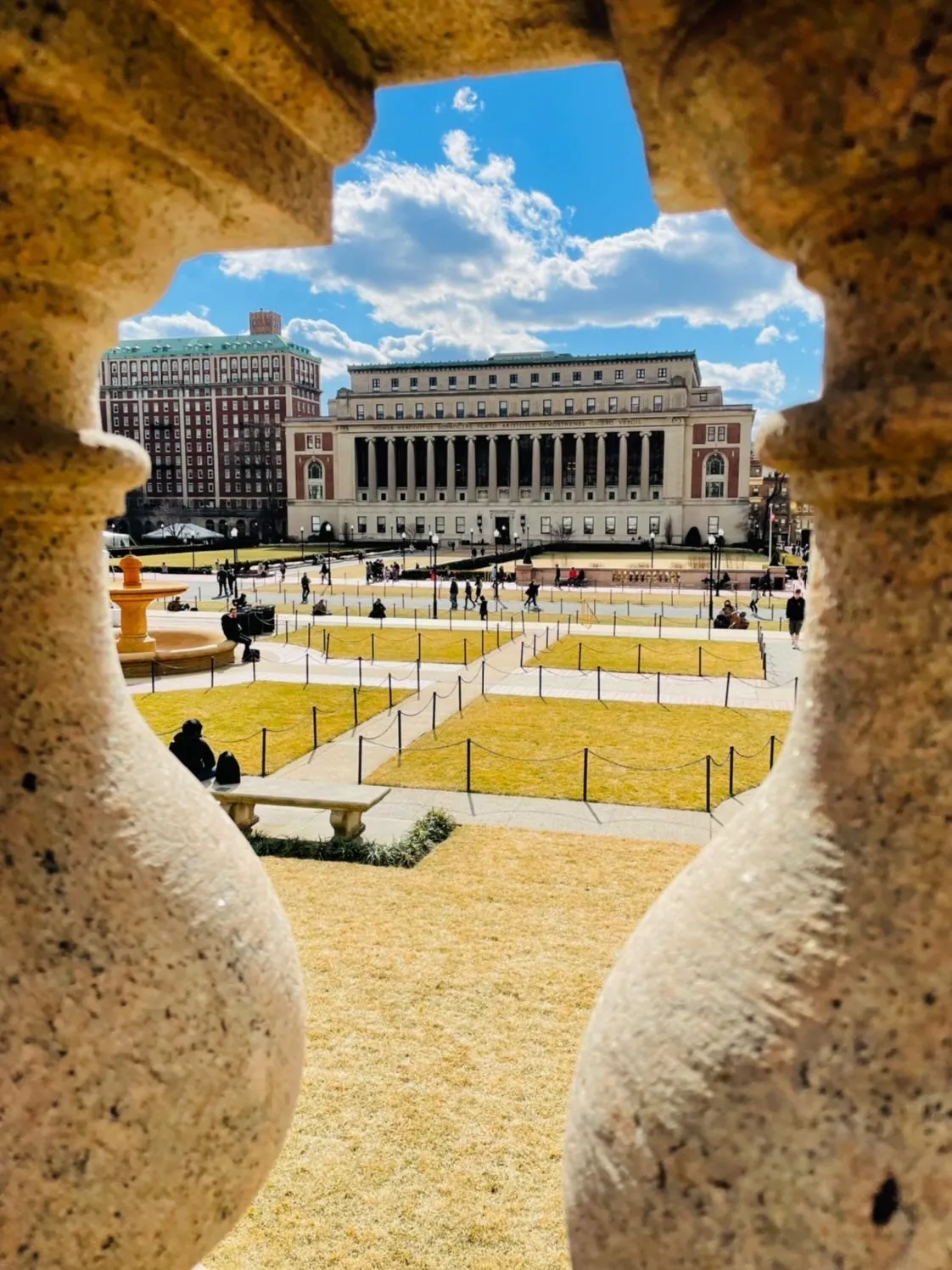 A view of Butler Library and Butler lawns between two concrete columns on a sunny day. 