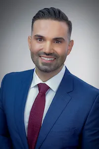 Carlos Galvez, 2022 graduate of Columbia College of Dental Surgery, wearing a blue blazer and a red tie
