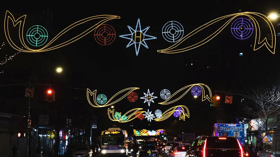 Festive Christmas lights hanging on lampposts across Harlem's 125th Street at night.