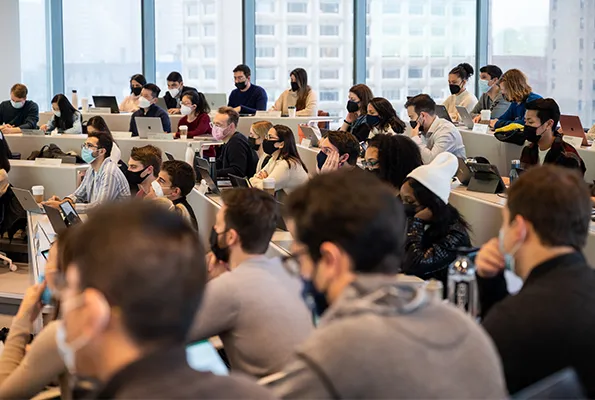 Masked students in a lecture hall in Kravis Hall. 