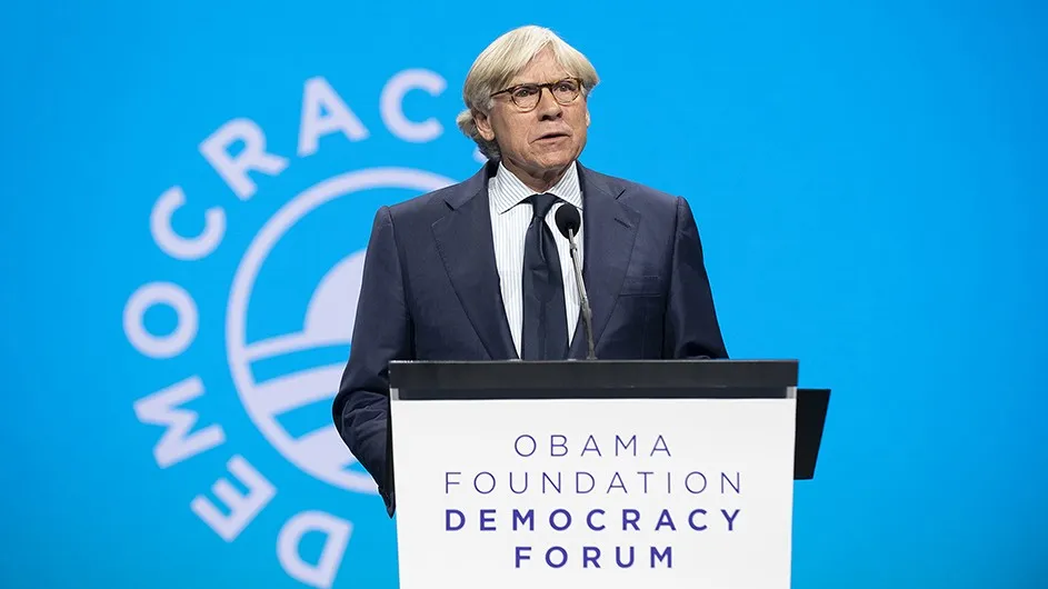 Lee C. Bollinger, a man with short, white hair, standing at a lectern. 