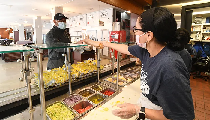 A Columbia Dining worker hands a sub to a hungry person in line. 