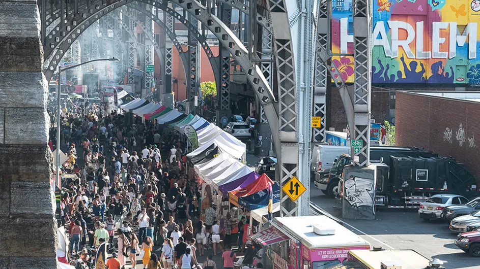 Uptown Night Market festival with people enjoying food and music under the arches of the aqueduct near Columbia Manhattanville.