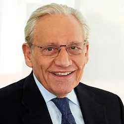 A man with short white hair, in a suit and tie. 
