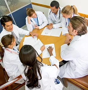 medical students sit around a table talking.