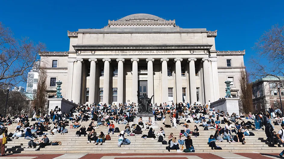 Dozens of students sit on the Low Library steps (Low Beach) while socializing or studying on a sunny warm winter day at Columbia University.