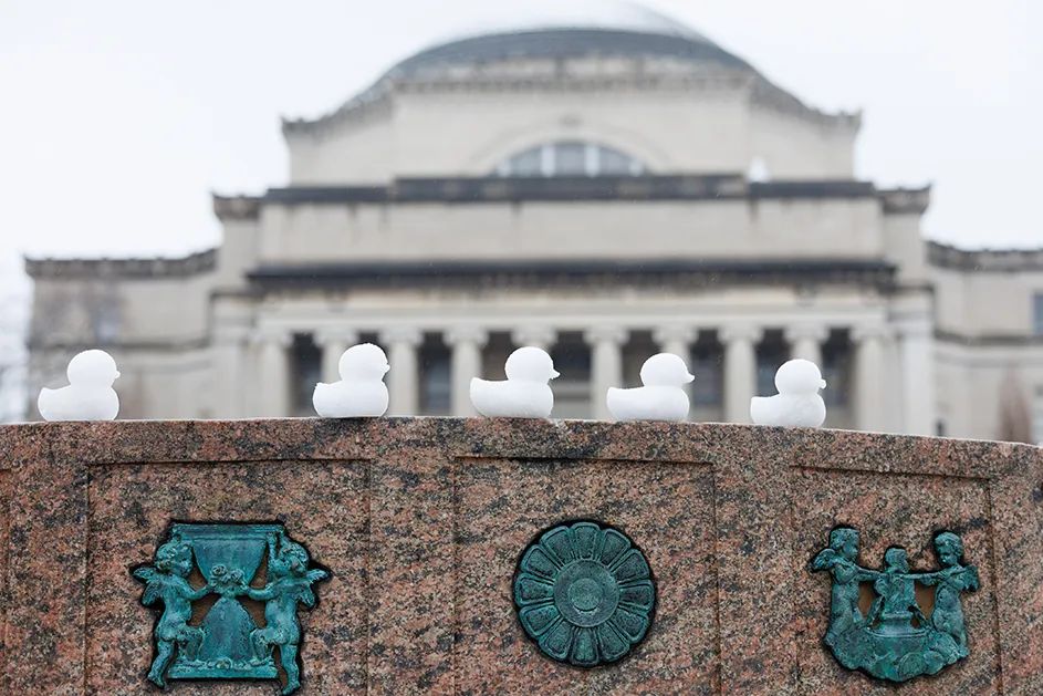 Five snow duck peeps on the Sundial sculpture with Low Library in the background on a cloudy winter day at Columbia University.