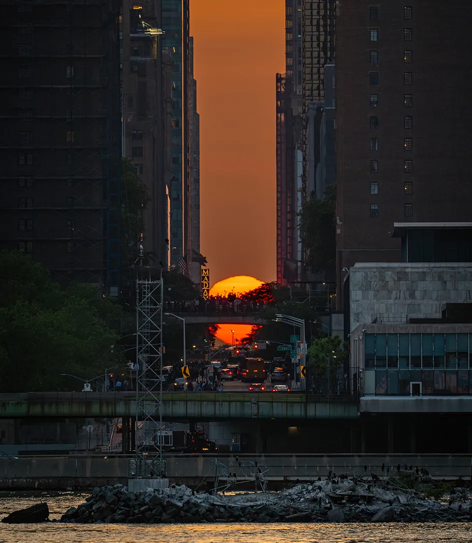 The sun setting on 42 Street between tall buildings in New York City during Manhattanhenge.

