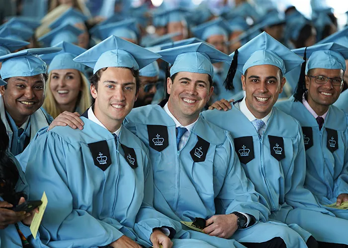 Columbia Business School graduates smile during the school's graduation ceremony.