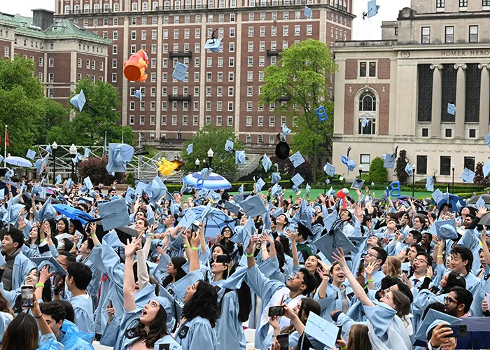 Graduates throw their mortar boards in the air on Morningside campus. 