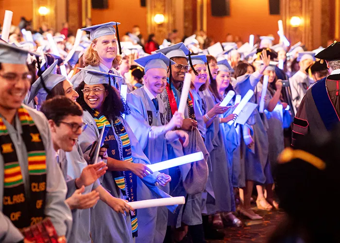Teachers College grads celebrate their graduation with blue glow sticks. 