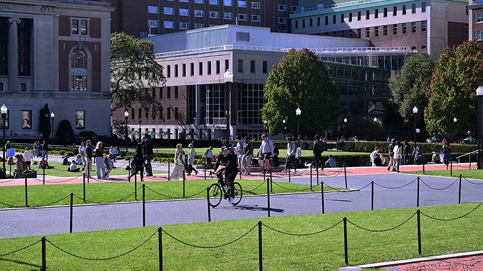 A view of Columbia's Morningside campus shows people on College Walk and South Lawn with Butler Library and Lerner Hall in the background.