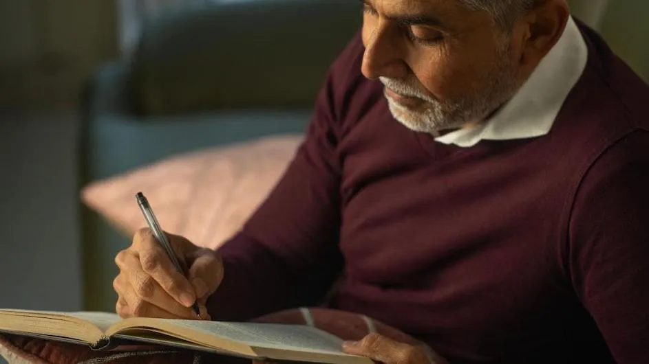 An older person writing in a book.