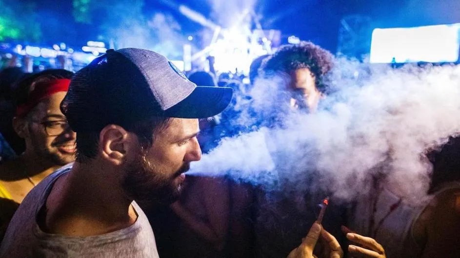 Image of a person holding a cannabis joint in a party setting.