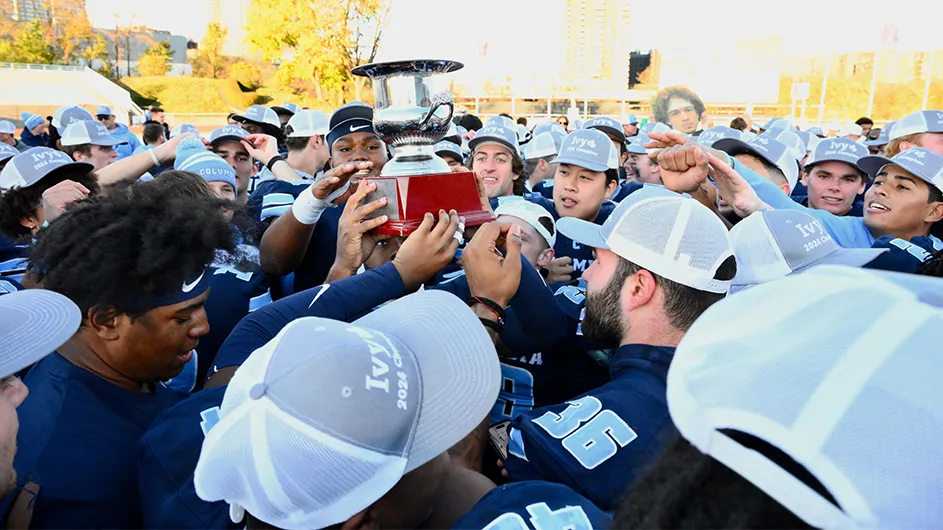 Columbia football players hoist an ivy league championship trophy