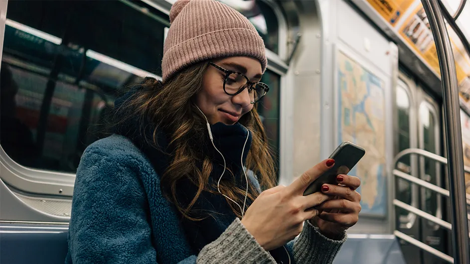 A woman listens to a podcast on the subway. 