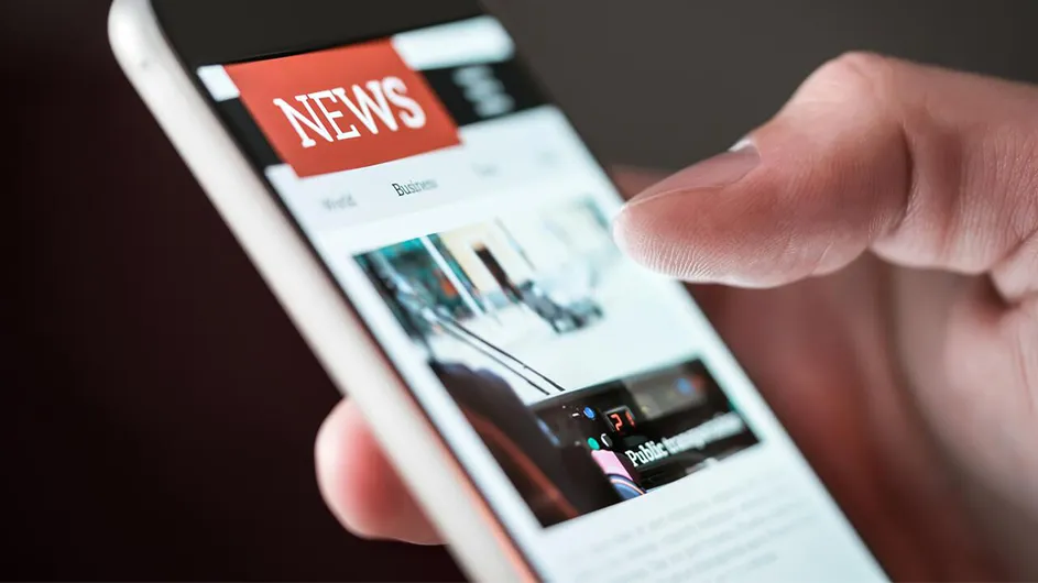 A finger touches a news app on a phone