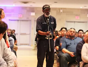 A Columbia staff member holds a microphone to ask a question at an all-staff University Operations meeting. 