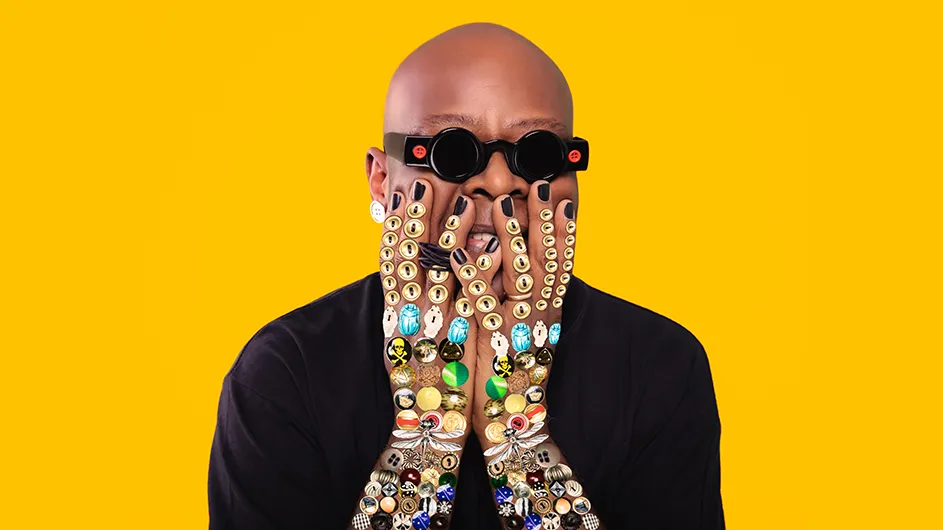 Harlem artist Beau McCall holding up his hands adorned with artistic buttons.