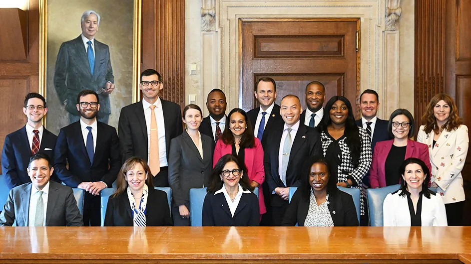 Several people smile and pose with Columbia President Shafik at a reception for White House Fellows in Low Library at Columbia University