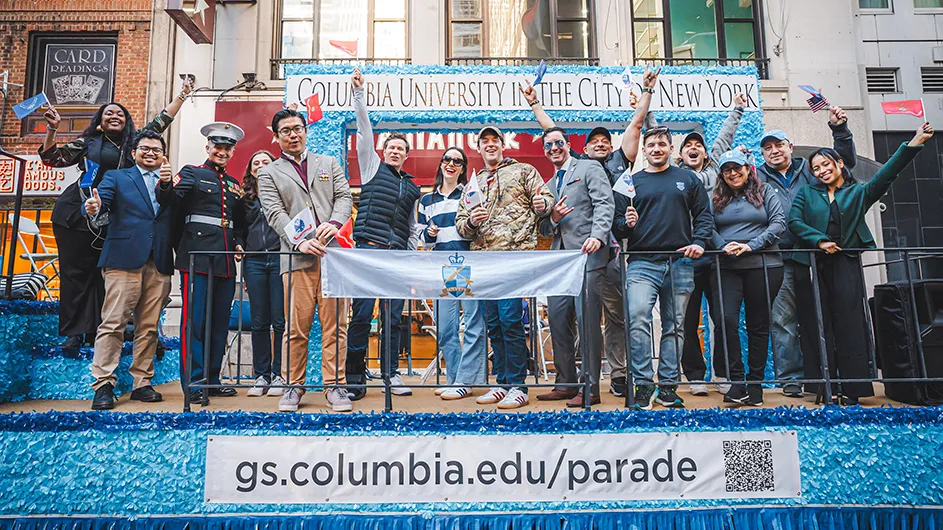 Columbia General Studies military veteran students waving on a parade float with Dean Lisa Rosen-Metsch at the 2024 Veterans Day Parade in New York City.