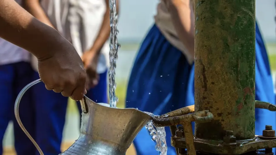 A person gathering drinking water from a well.
