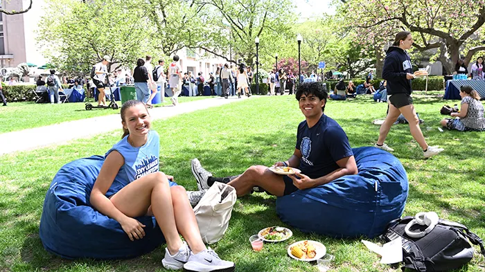 Two students sit on blue bean bags with their lunch.