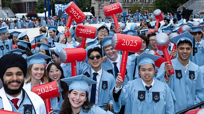 Columbia Engineering students hold up inflatable red hammers with "2025" emblazoned on them.