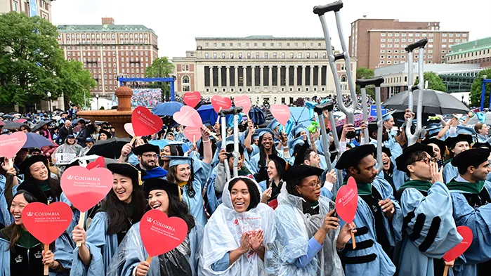 Graduates of Vagelos College of Physicians and Surgeons wave heart decals and inflatable crutches. 