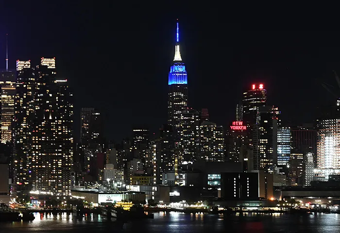 The New York City skyline as seen from New Jersey with the Empire State Building lit blue.