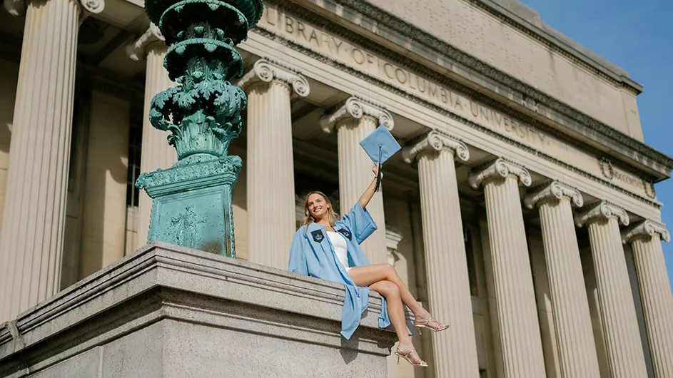 Chloe Harrah tips her mortar board on the steps of low library. 
