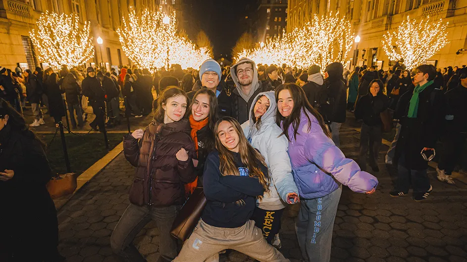 Students pose for a photo on College Walk during the tree lighting ceremony with a large crowd in the background