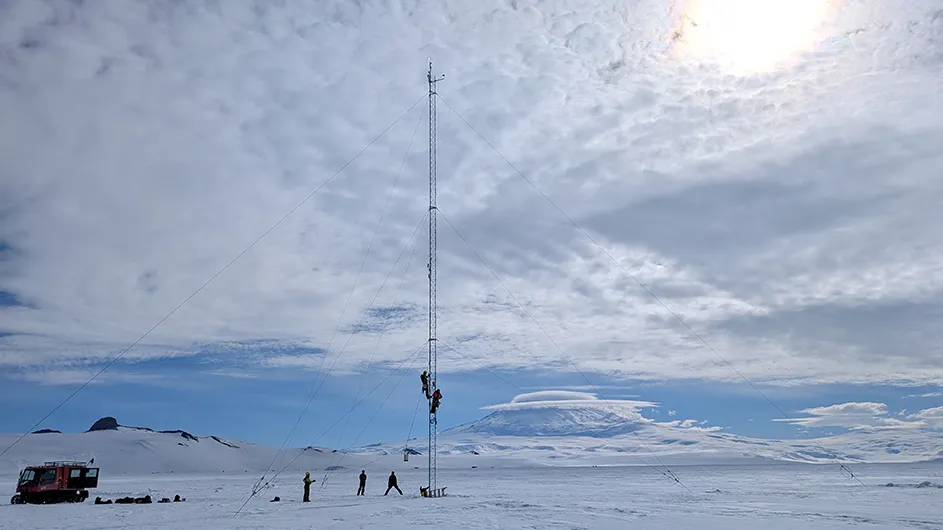 Five Columbia climate & engineering researchers set up a tower to measure winds and snow on the McMurdo Station in Antarctica with the sun shining through the clouds. 