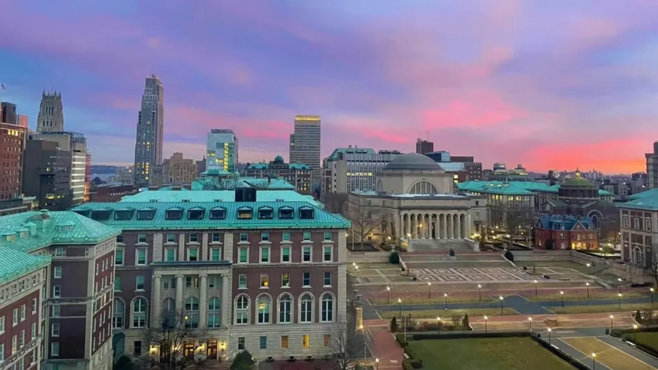 Morningside campus showing Low Library, South Lawn, Pulitzer Hall, and other buildings against a pink and purple sunrise sky at Columbia University.