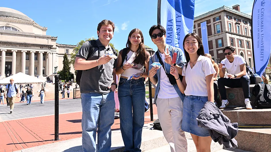 Four university students hold up ice cream and smile at Treats on the Plaza near the Sundial and Low Library at Columbia University on a sunny warm day. 