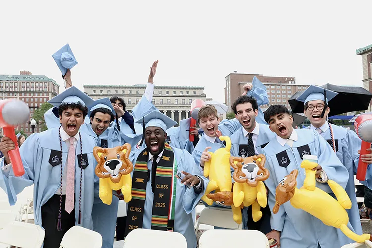 Eight university students wearing light blue graduation regalia cheer and roar while holding inflatable balloon lions and balloon hammers at Columbia University Commencement on Morningside campus. 