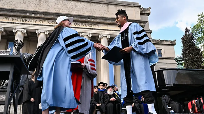 A woman greets a man on the stage of Columbia's Commencement. 