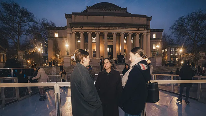 Three people chat outside of a temporary ice rink on Columbia's campus.