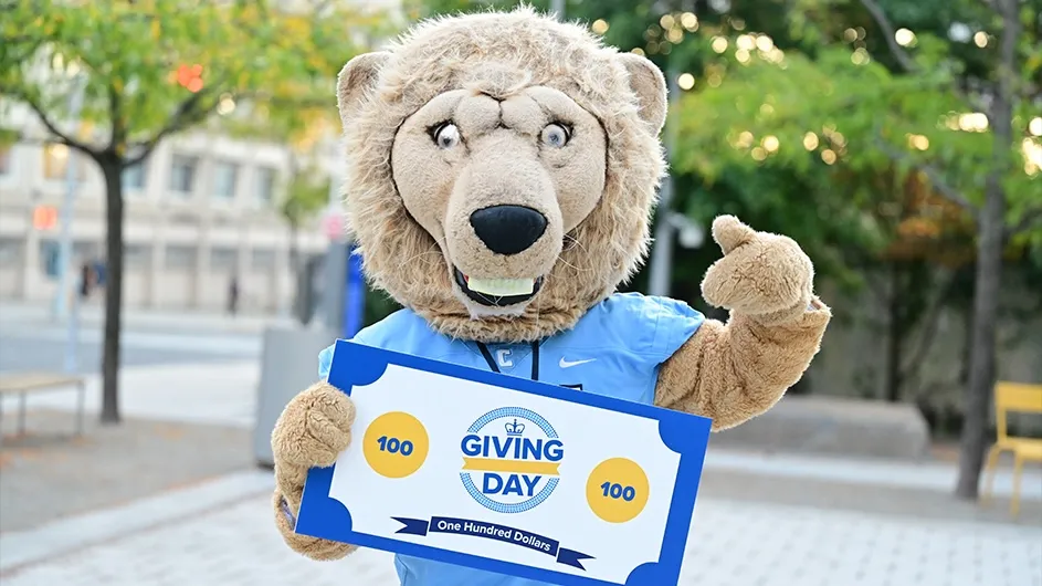 Columbia University mascot RoarEE stands with a large novelty check for Giving Day 2026.