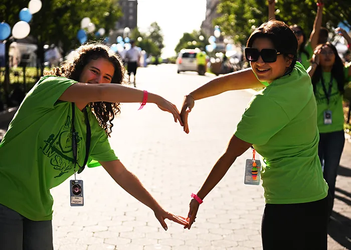 Two NSOP leaders make a heart with their arms and hands.